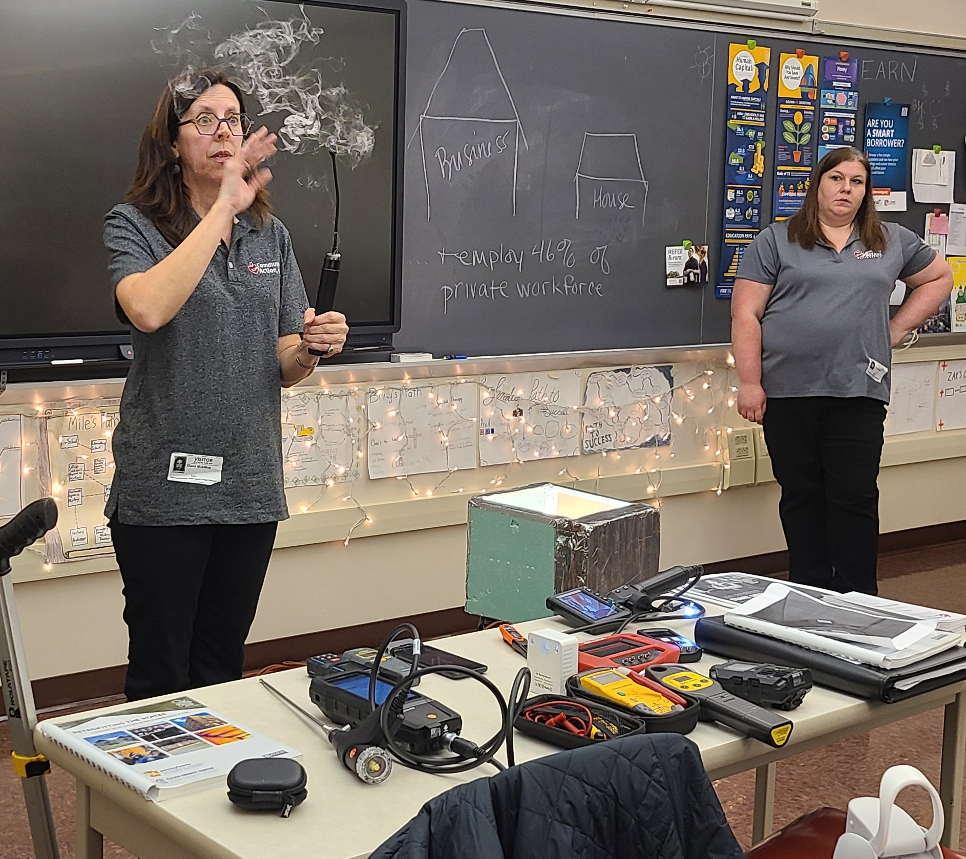 Diana McKillop, Quality Control Inspector for Community Action, Inc.’s Weatherization Program, demonstrates an air tracer/smoke tester used by Weatherization staff to find air leaks and to determine if furnaces and hot water tanks are drafting correctly.  Tina Kephart, Weatherization Director, looks on.